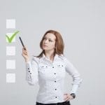 Young business woman checking on checklist box. Gray background. Checklist of Important Items