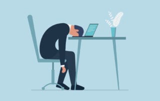 Frustrated Man at Desk with Head Down on a Laptop
